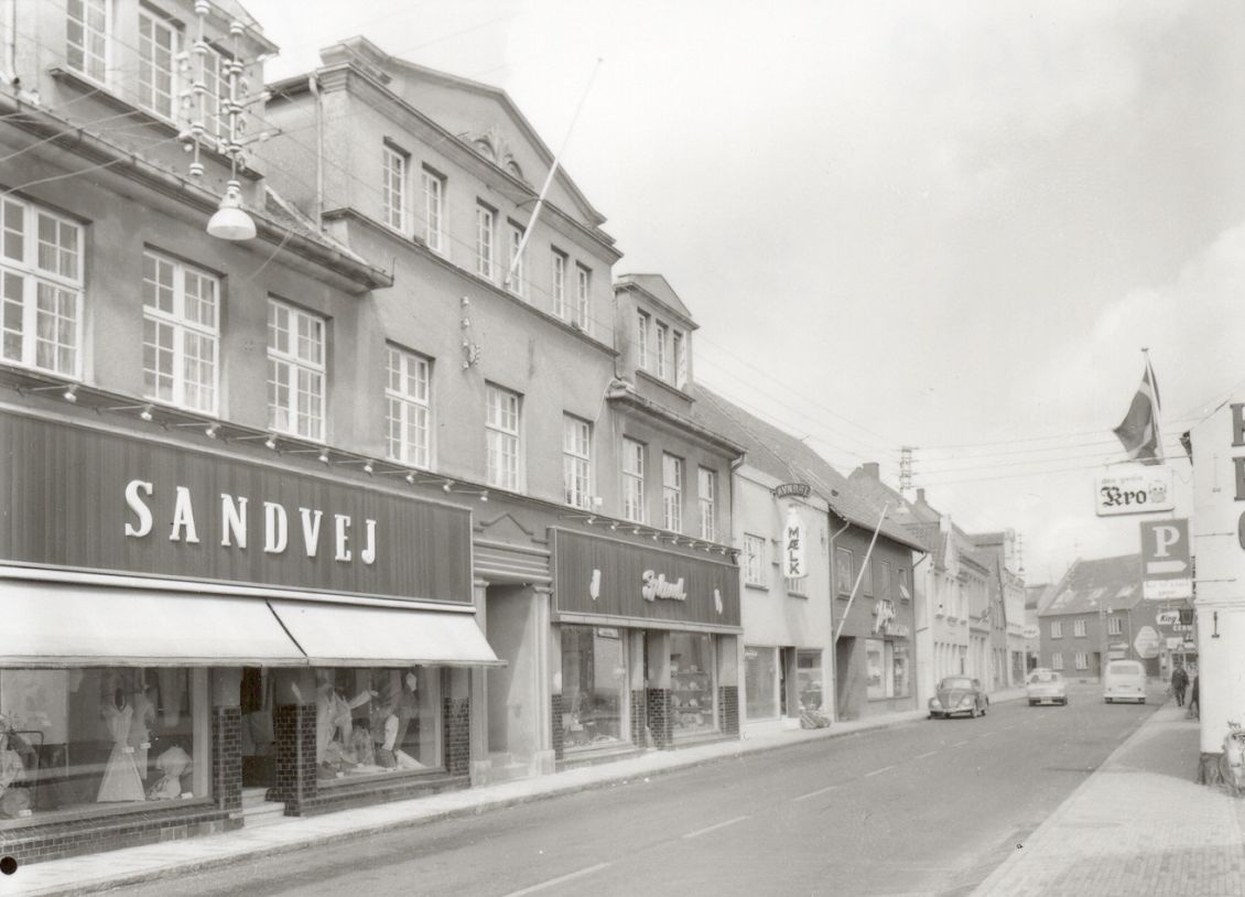 Slotsgade 1950 med Wilhelm Sandvejs dametøjs butik og Jørgen Iplands Isenkram's butik.